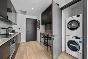A modern kitchen with a built-in washing machine, a dining area with bar stools, and a door leading to another room. - 23rd Floor E11EVEN 1BR with Balcony & Views (Miami)