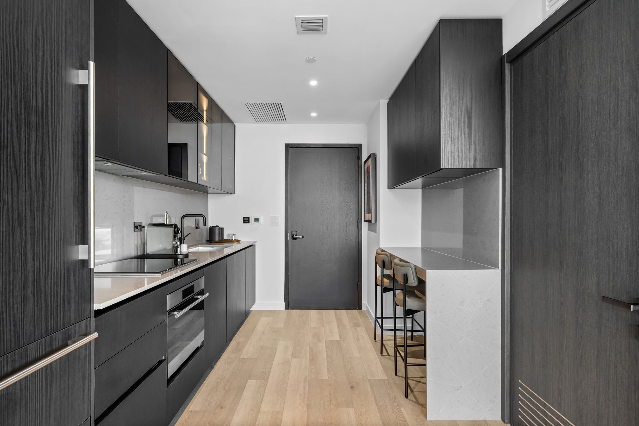 Una cucina moderna con mobili scuri, un'isola centrale e un bancone con sgabelli.