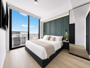 A modern bedroom with a large bed, a TV mounted on the wall, and a city view through large windows. - 23rd Floor E11EVEN 1BR with Balcony & Views (Miami)