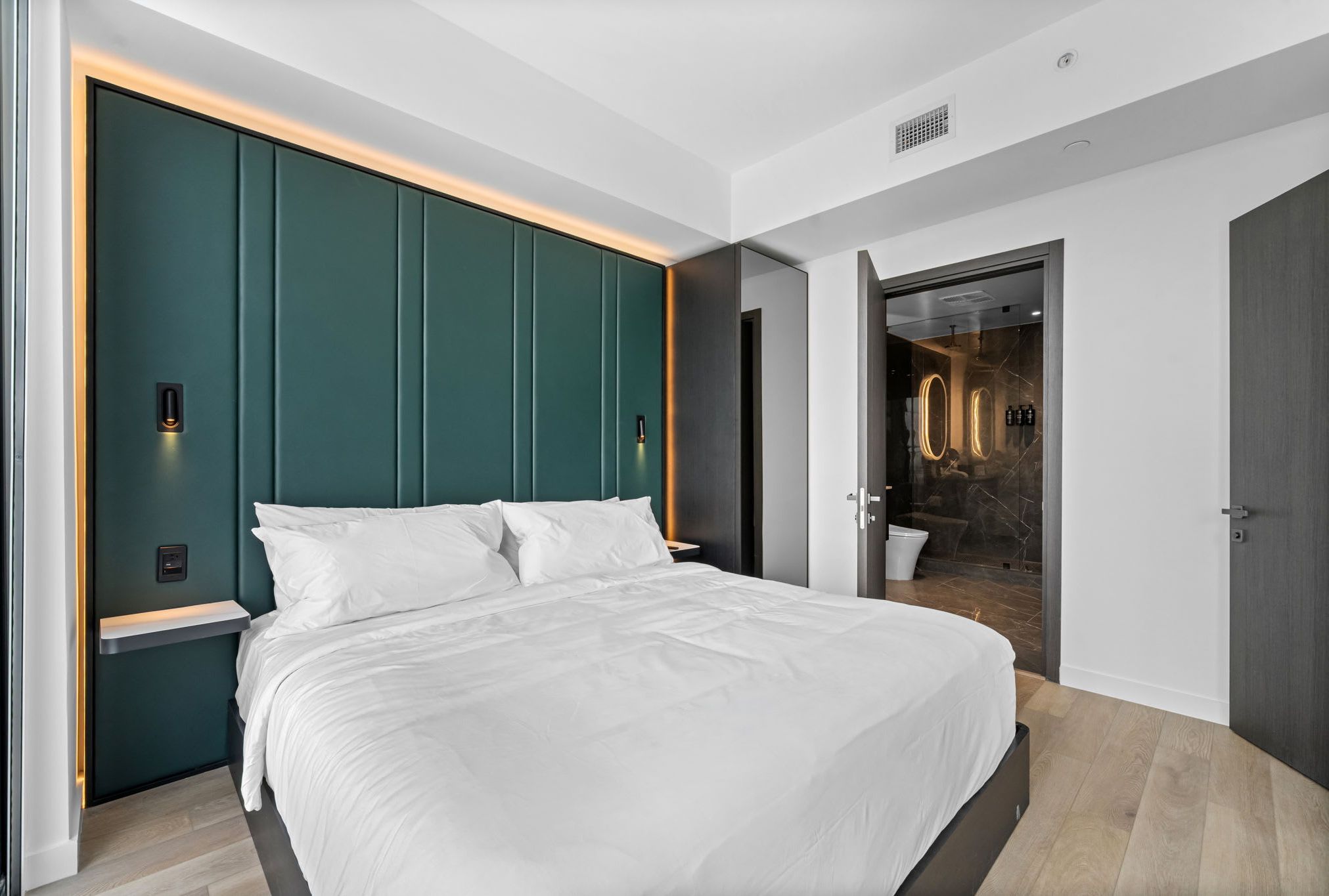 Bed with white linens and a green paneled headboard.