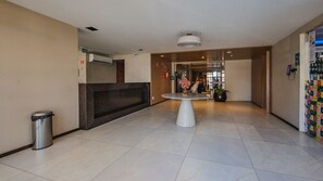 En hotellobby med reception, skraldespand, et bord med en vase og en væg med et farverigt mønster.