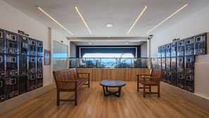 A modern interior with wooden flooring, a round table, two wooden chairs, and a view through a glass partition. - Apto c Piscina e Academia a 800m Praia de Arma o (Salvador)