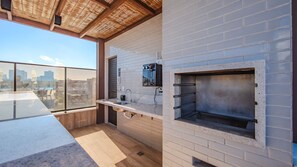 A rooftop terrace with a built-in grill, a sink, and a view of the cityscape. - Apto c Piscina e Academia a 800m Praia de Arma o (Salvador)