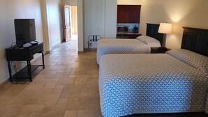 Une chambre d’hôtel avec deux lits, un bureau avec une télévision, une kitchenette et une salle de bain.