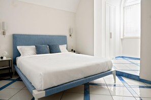 Ein modernes Schlafzimmer mit einem großen Bett, weißer Bettwäsche und einem blauen Kopfteil.