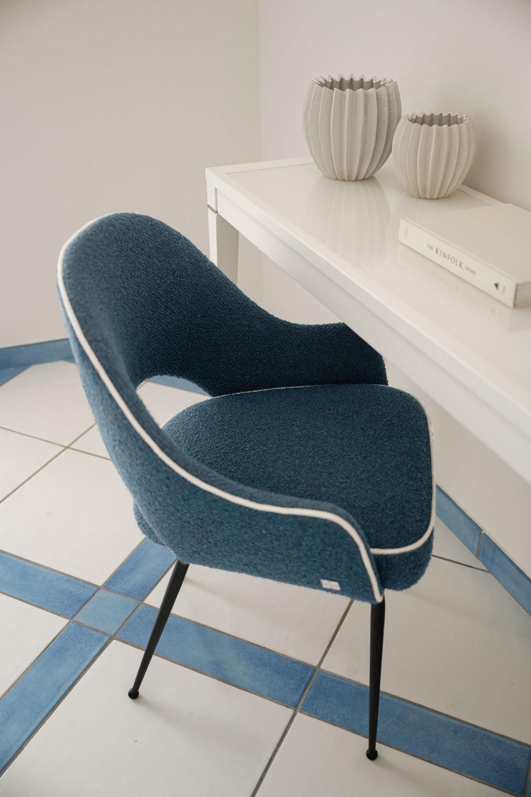 A chair with a dark fabric and metal frame, positioned on a tiled floor with blue and white tiles.