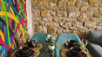 Un comedor con pared de piedra, un cuadro abstracto de colores y sillas color turquesa.