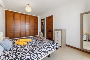 Un dormitorio con cama, armario, cómoda y espejo.