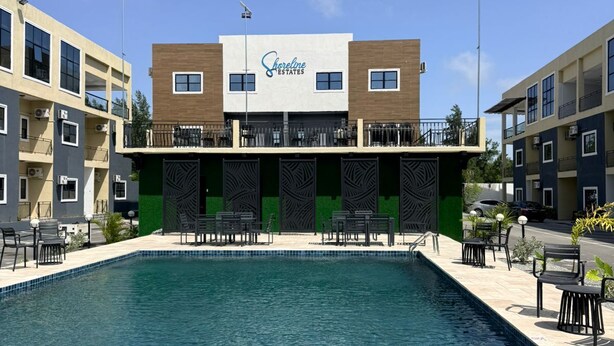 Un edifici amb un rètol que diu 'Shoreline Estates' sobre una piscina i gandules amb taules.