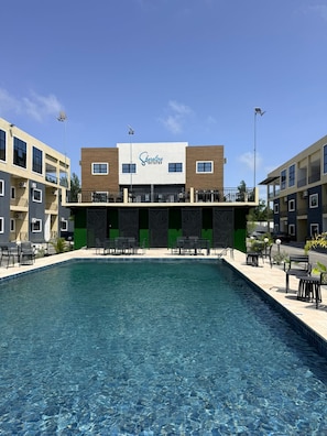 A building with a sign reading 'Shoreline Estates' above a swimming pool with lounge chairs and tables.