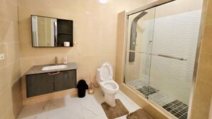 Un bany amb vàter, rentamig i zona de dutxa amb envàs de vidre.