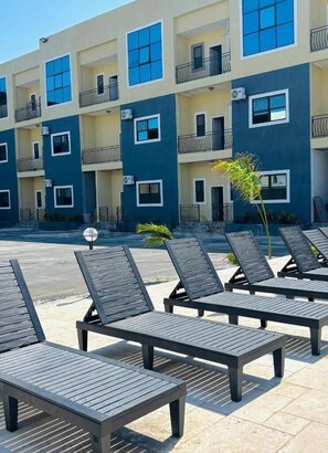 A multi-story building with balconies, outdoor seating, and a swimming pool.