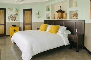 Une chambre d’hôtel avec un grand lit, deux tables de chevet, une petite table, une lanterne décorative et une étagère murale sur laquelle sont disposés divers objets.