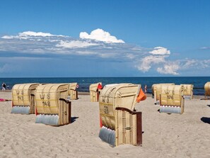 Beach chairs with numbers on them, arranged on a sandy beach with the ocean in the background. - Holiday Apartment With 3 Bedrooms (Heiligenhafen)