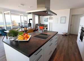 A modern kitchen with a central island, white cabinetry, and a view to the outside. - Holiday Apartment With 3 Bedrooms (Heiligenhafen)