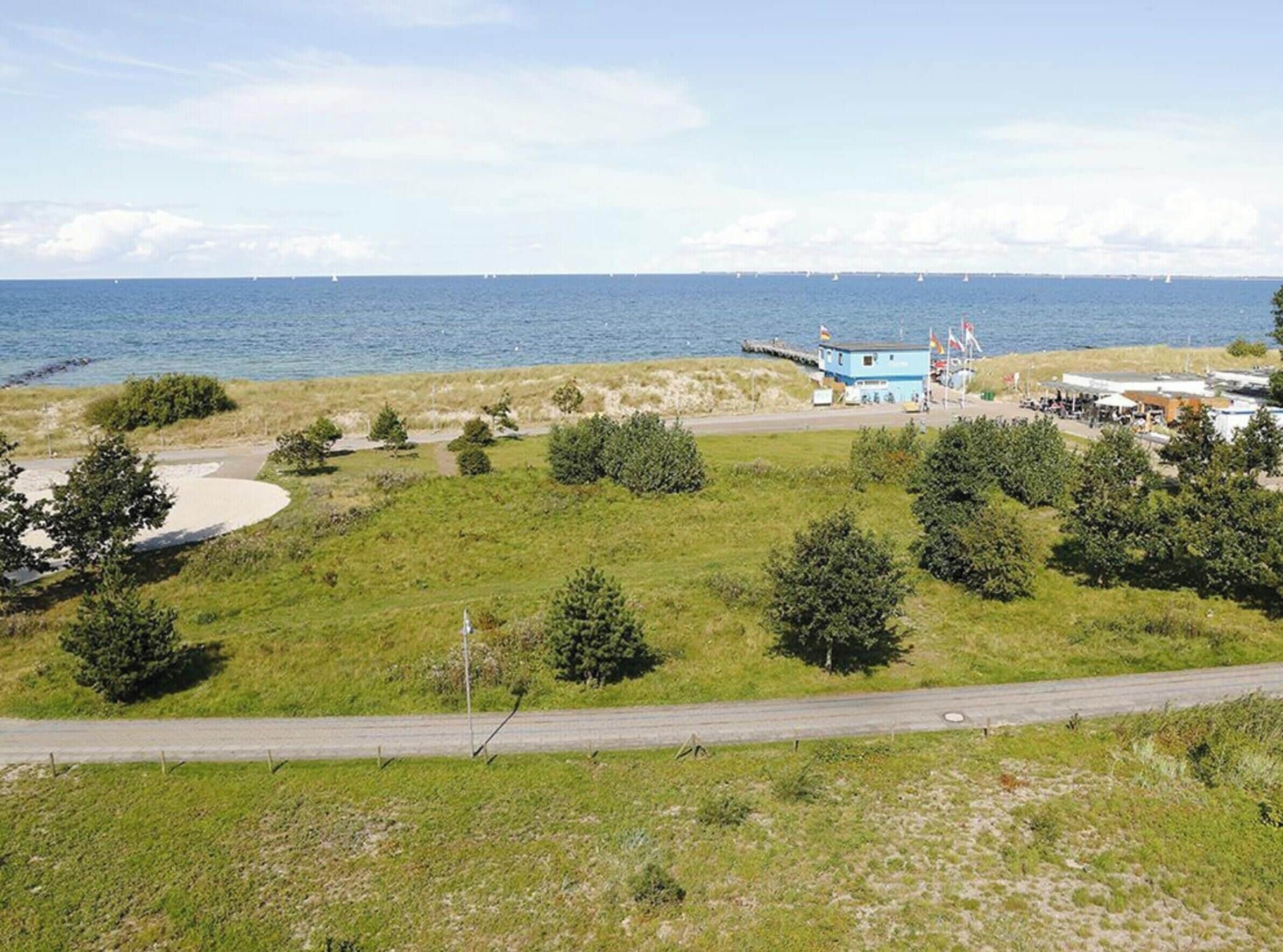 Ein Küstenanwesen mit einer Rasenfläche, einem kleinen Gebäude und einer Straße, die zum Meer führt.