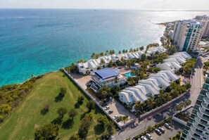 A coastal resort with multiple white buildings, a swimming pool, and a view of the ocean. - Freebird by the beach (Cupecoy)