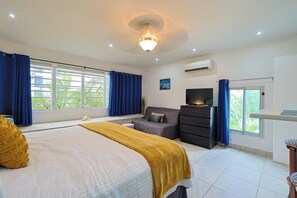 A bedroom with a bed, a TV, a dresser, and a window with curtains. - Freebird by the beach (Cupecoy)