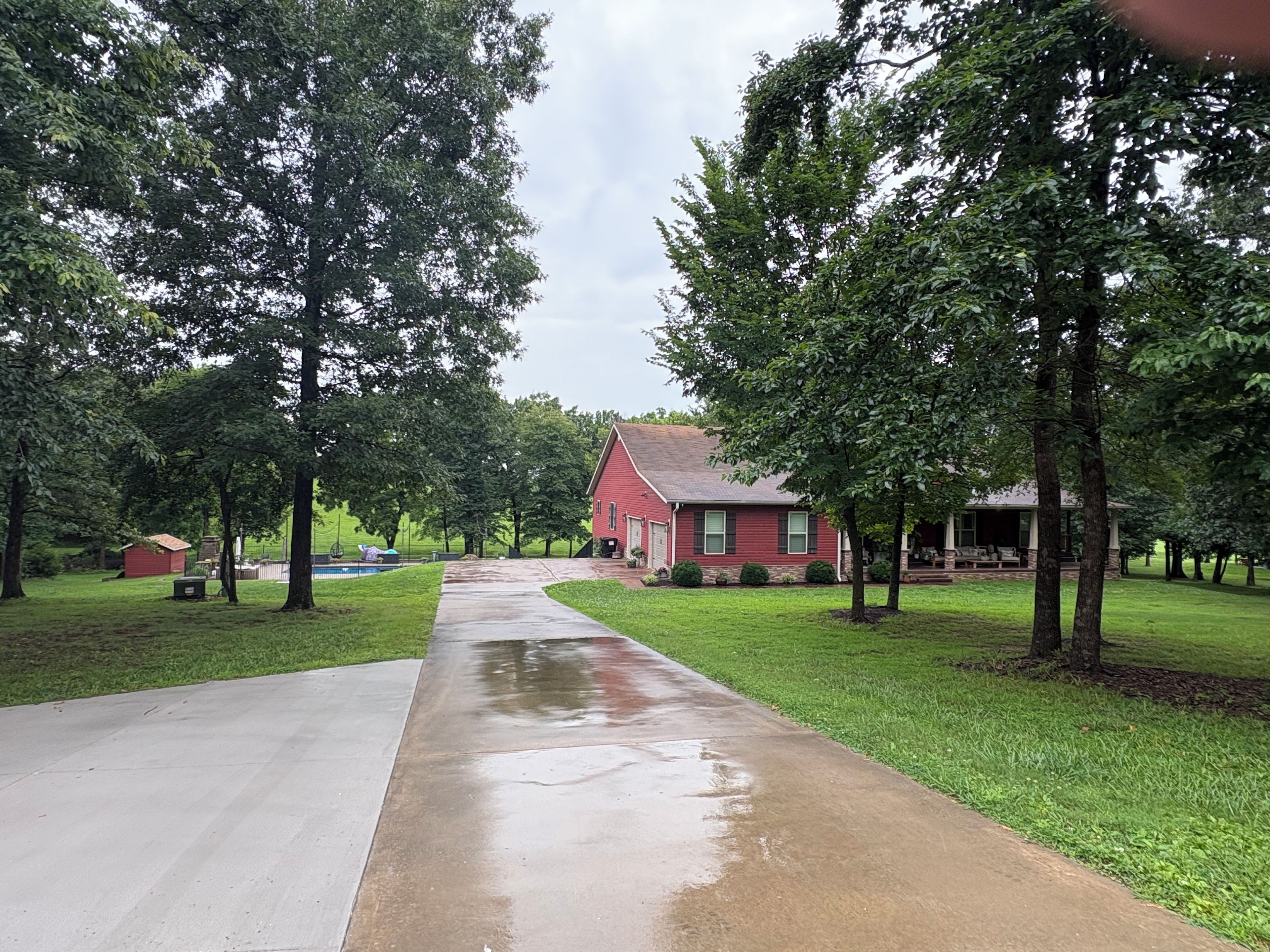 A residential area with a red house, a concrete driveway, and a grassy lawn.