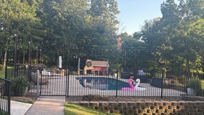 Un espacio exterior vallado con una piscina, una decoración de flamenco rosa y un muro de ladrillo.
