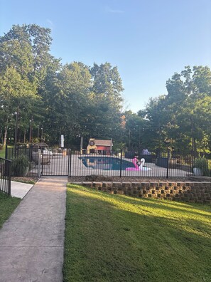 Área externa cercada com piscina, uma decoração de flamingo rosa e um muro de tijolos.