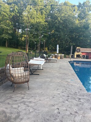 An outdoor patio with a pool, lounge chairs, and a stone fireplace. - Honey Bunny Biscuit Farm in NW Arkansas (Hindsville)
