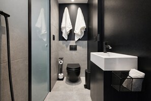 Ein modernes Badezimmer mit Duschkabine aus Glas, Toilette, Waschbecken und Handtuchhalter.