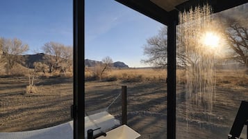 Ein Badezimmer mit großem Fenster, Waschbecken und Dusche.