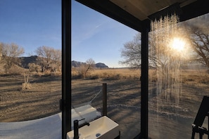 A bathroom with a large window, a sink, and a shower.