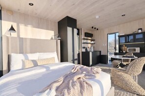 Habitació d'hotel moderna amb un llit gran, escriptori, cadira i televisió.