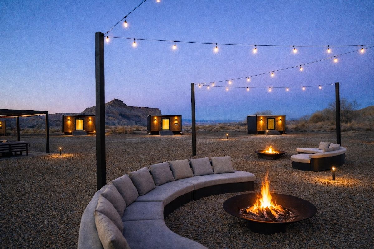An outdoor seating area with a curved sofa, a fire pit, and string lights.