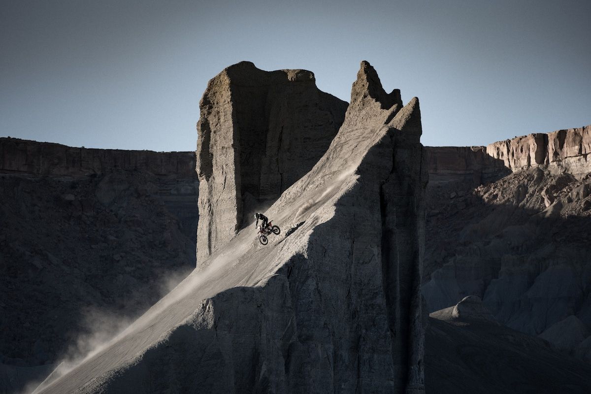 A person on a dirt bike descending a steep, rocky slope.