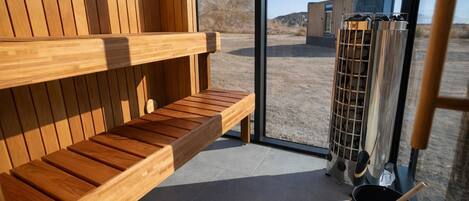 A sauna room with wooden benches and a glass door leading outside.