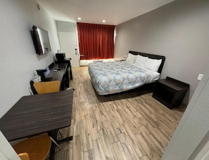Une chambre d’hôtel avec un lit, un bureau, une chaise et un téléviseur.