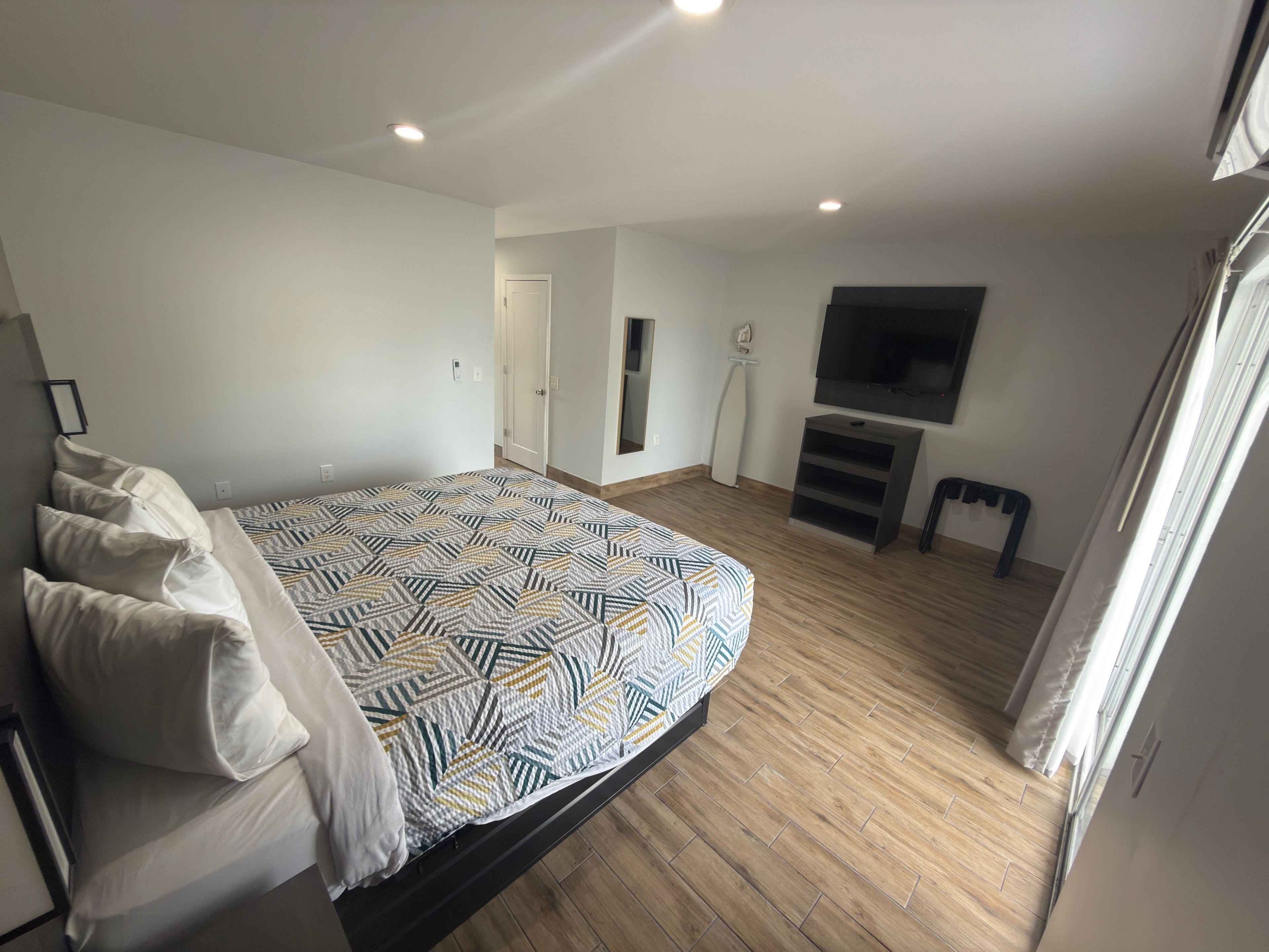 Ein Schlafzimmer mit einem Bett, einem Fernseher und einer Tür.