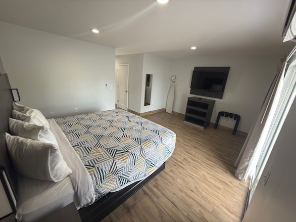 A bedroom with a bed, a television, and a door.