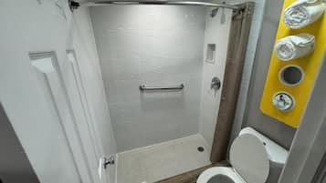 A bathroom with a shower, toilet, and towel rack.