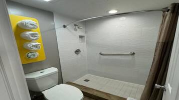 A small bathroom with a toilet, a shower with a glass door, and a yellow towel rack.
