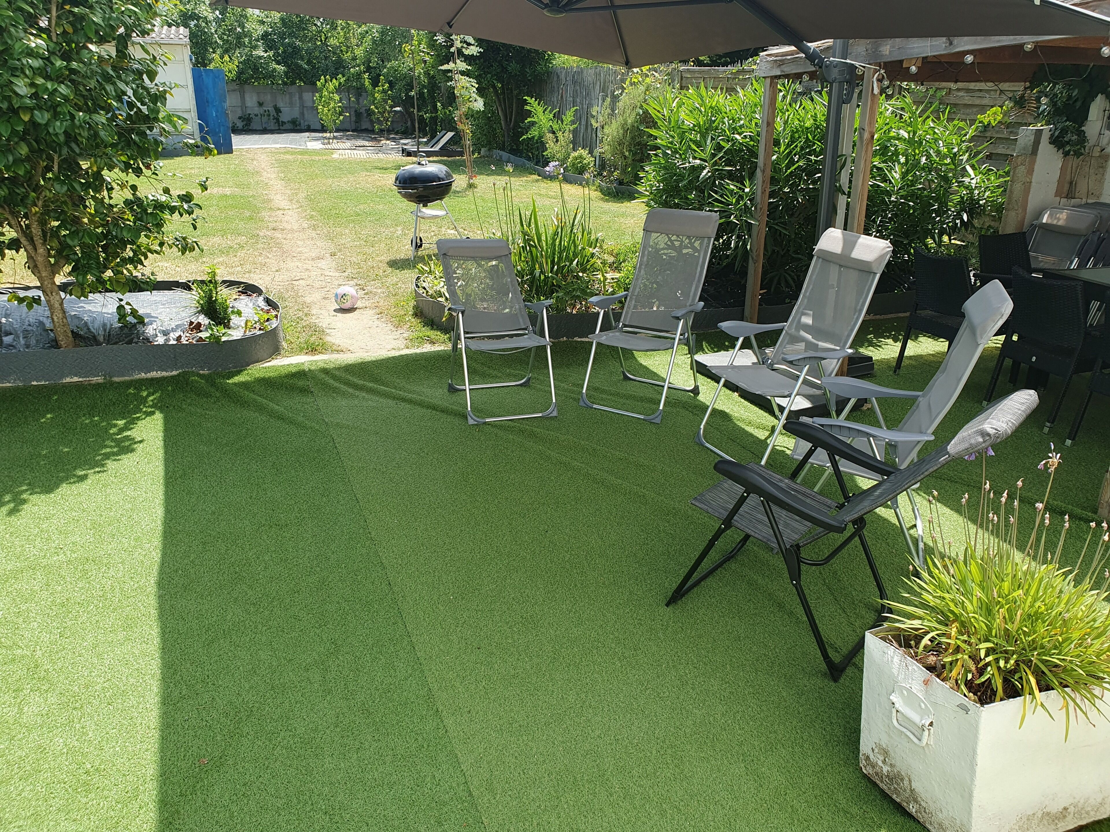 A patio with artificial grass, outdoor furniture, and a barbecue grill.