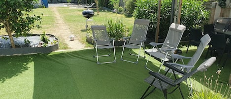 A patio with artificial grass, outdoor furniture, and a barbecue grill.