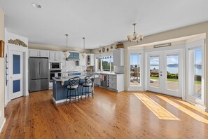 A spacious kitchen with a central island, stainless steel appliances, and a view of the outdoors. - Chamber's Bay Lodging (University Place)