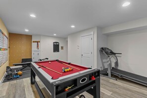 A pool table with balls, a treadmill, and a door. - Chamber's Bay Lodging (University Place)