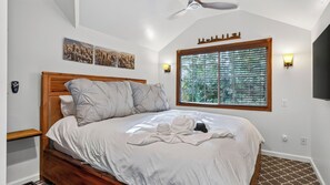 Una camera da letto con una testiera in legno, un letto grande con biancheria da letto bianca, una finestra con persiane e luci a parete.