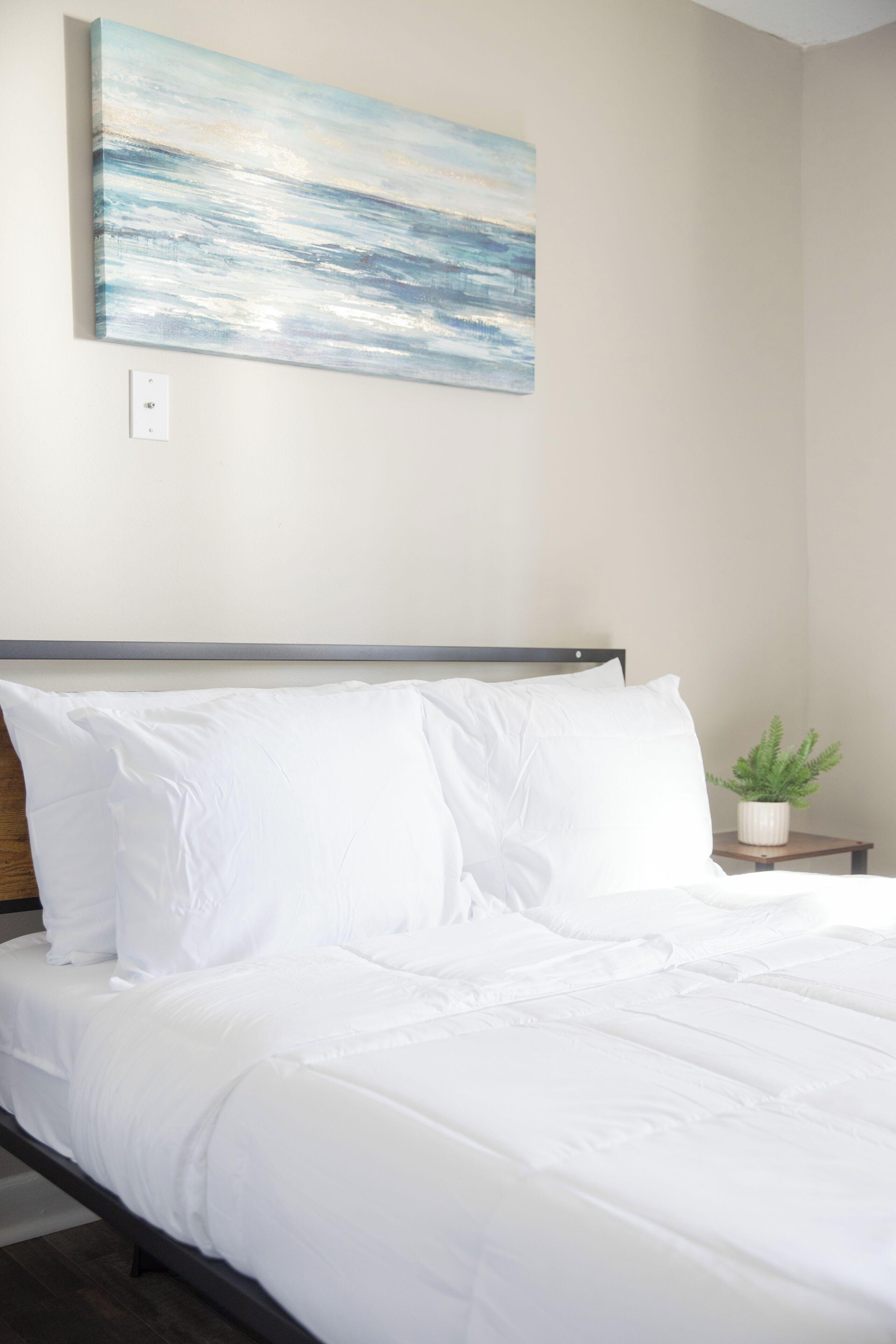 Un lit bien fait, avec du linge de lit blanc, dans une pièce au design simple et épuré.