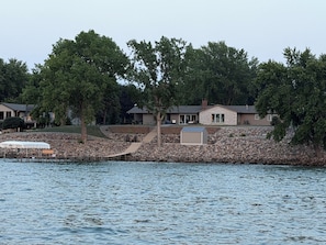 A lakeside property with a dock, stone walls, and multiple houses.