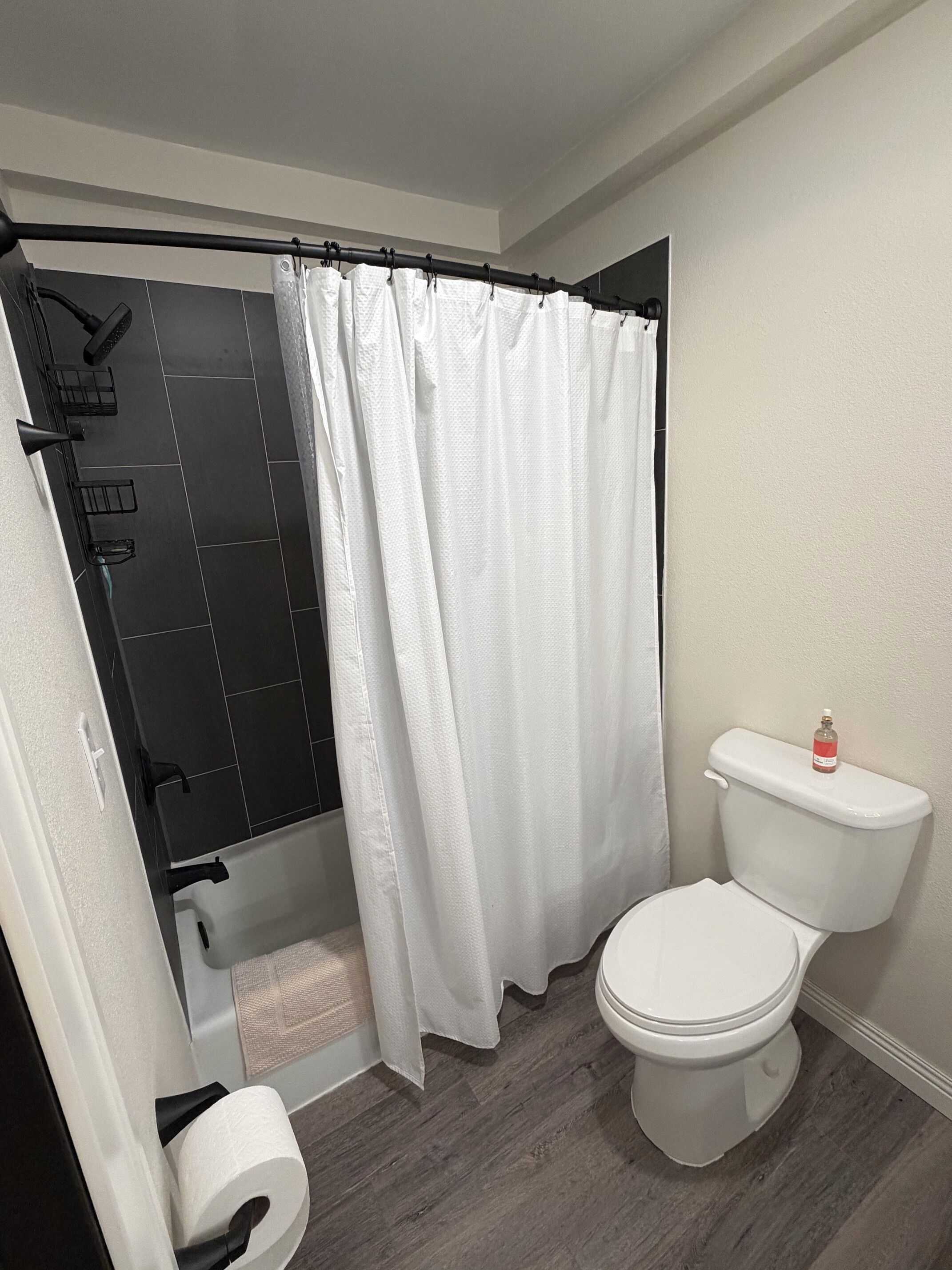 Un baño con ducha, inodoro y un perchero para toallas.