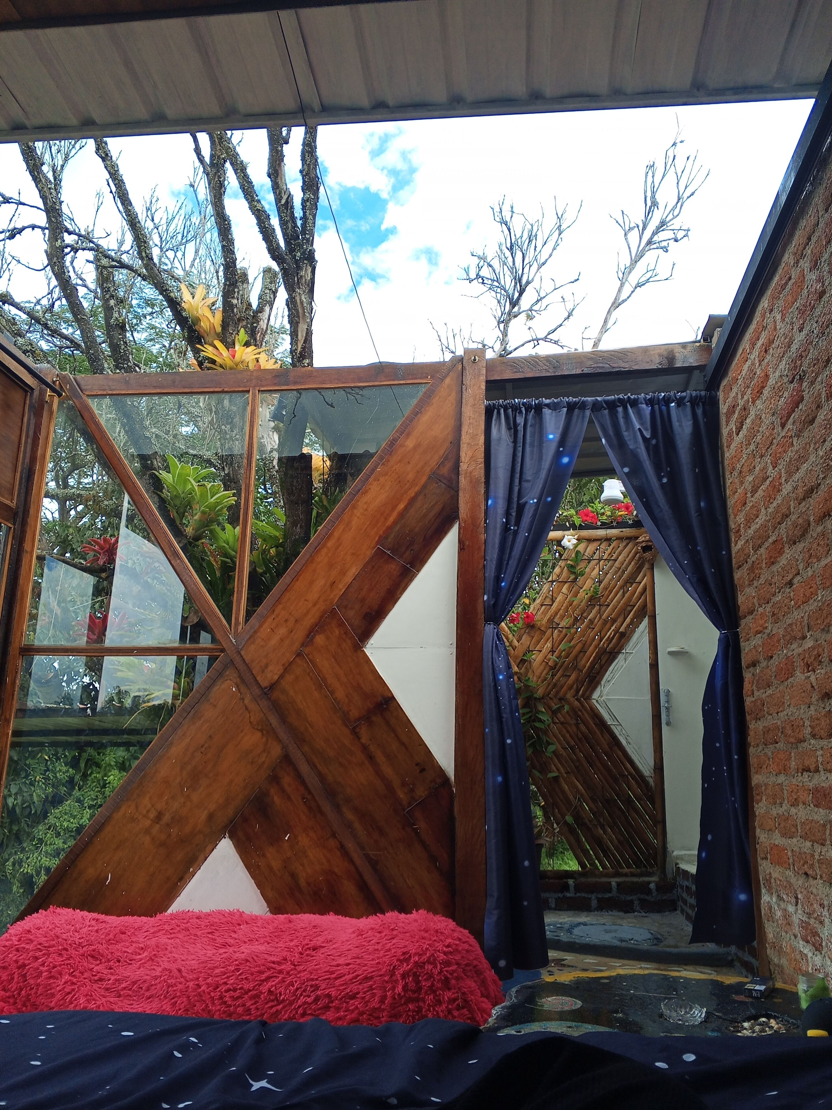 Una habitación con una cama, un separador de madera y vistas al exterior.