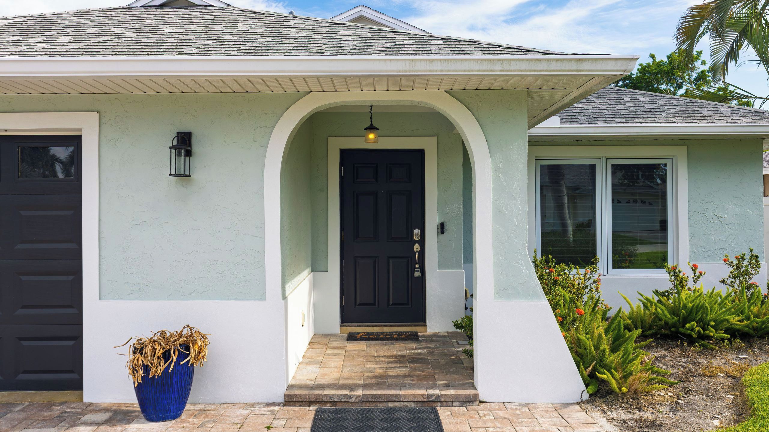 A house with a dark front door, a light-colored exterior, and a small porch.