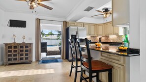 A kitchen with a dining area, a refrigerator, a coffee maker, and a bottle of water. - Lanai & Light by Avantstay Naples Park Retreat Private Pool + Lanai Near Vanderbilt Beach (Naples)