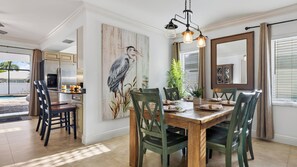 A dining area with a wooden table, chairs, and a painting of a bird. - Lanai & Light by Avantstay Naples Park Retreat Private Pool + Lanai Near Vanderbilt Beach (Naples)